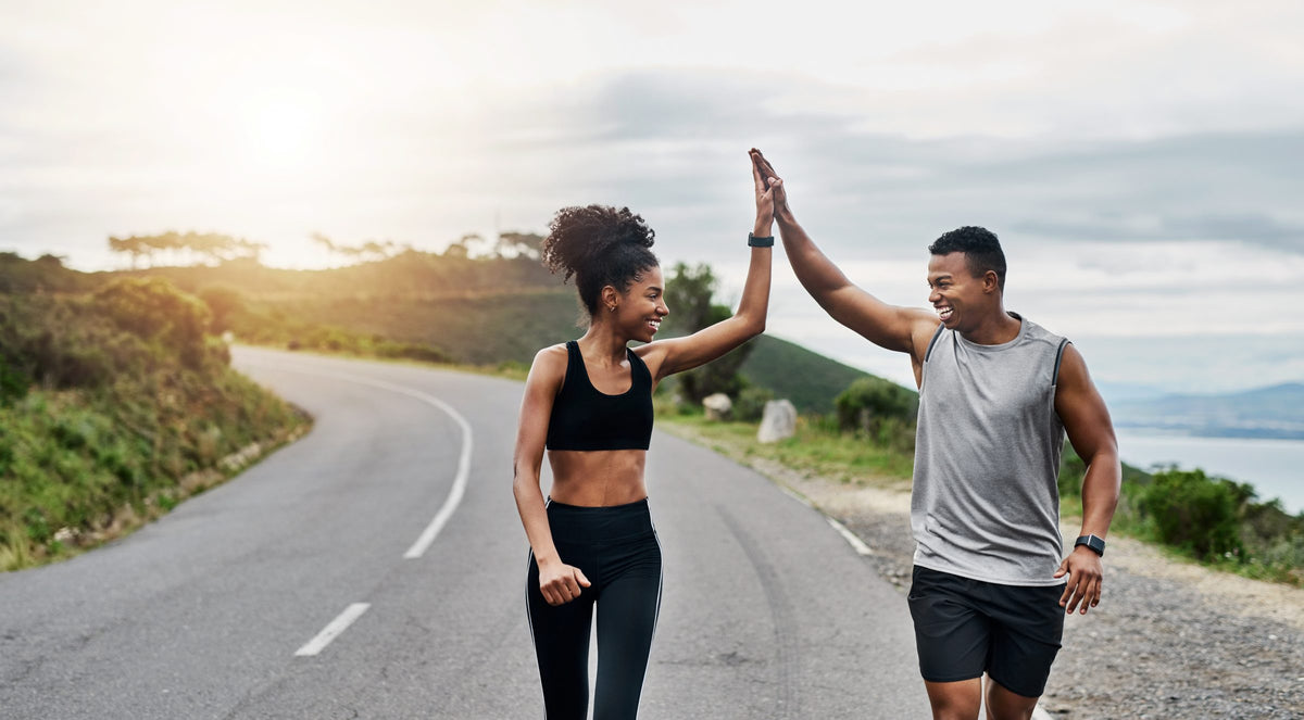 A healthy, active couple high-five on an outdoor run
